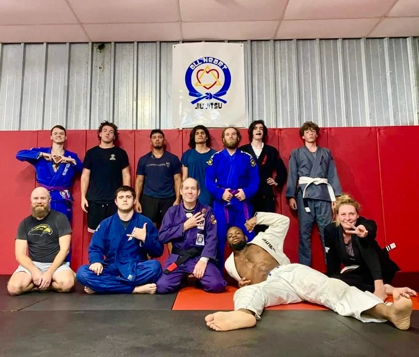 All Heart Jiu Jitsu adult class group photo with the gym banner